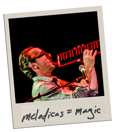 Polaroid of Gary playing a red melodica into a microphone, captioned “melodicas = magic”